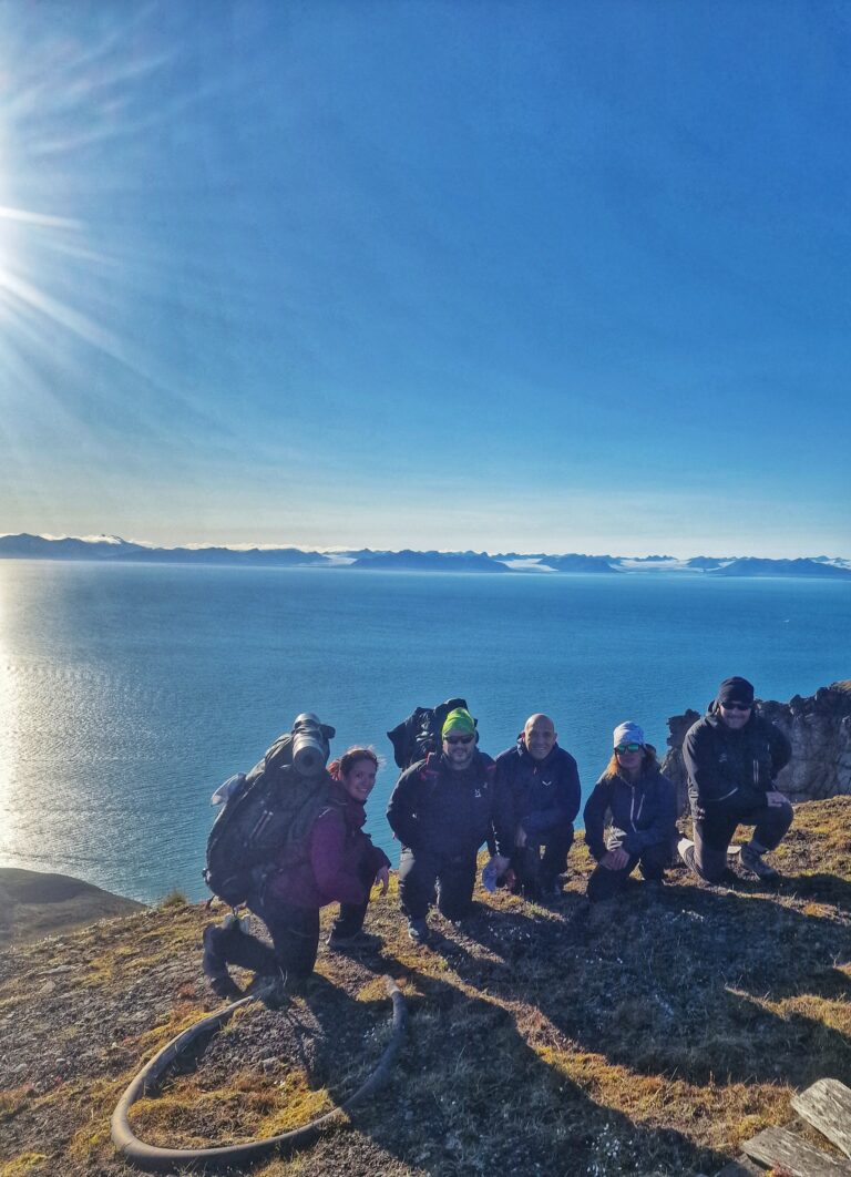 Gruppo di persone in cima ad una montagna e il mare sullo sfondo