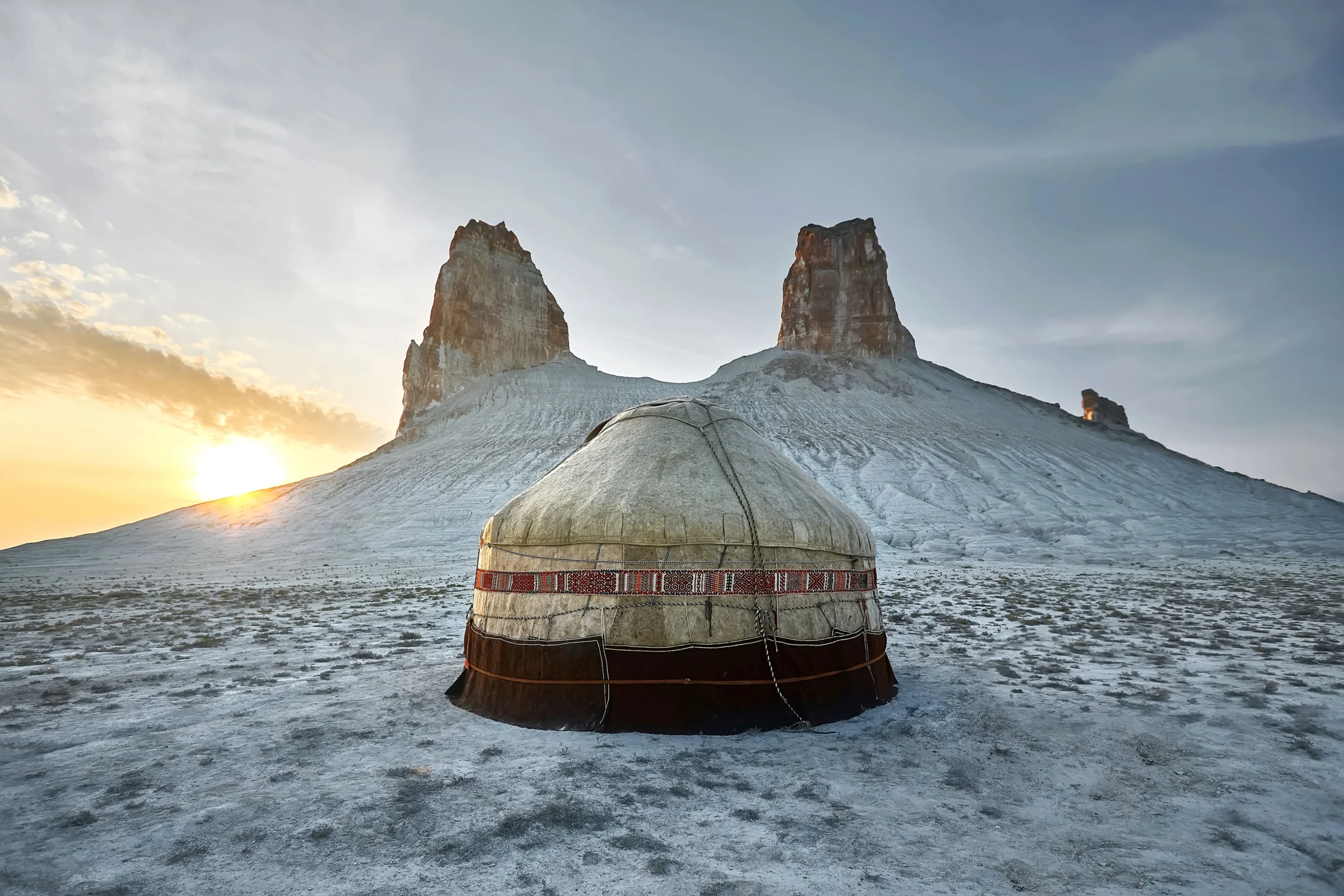 Yurta davanti a montagna appuntita e sole sullo sfondo