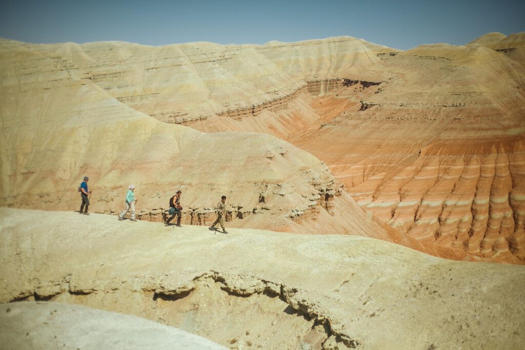 Persone che camminano sulla cresta di una montagna color sabbia